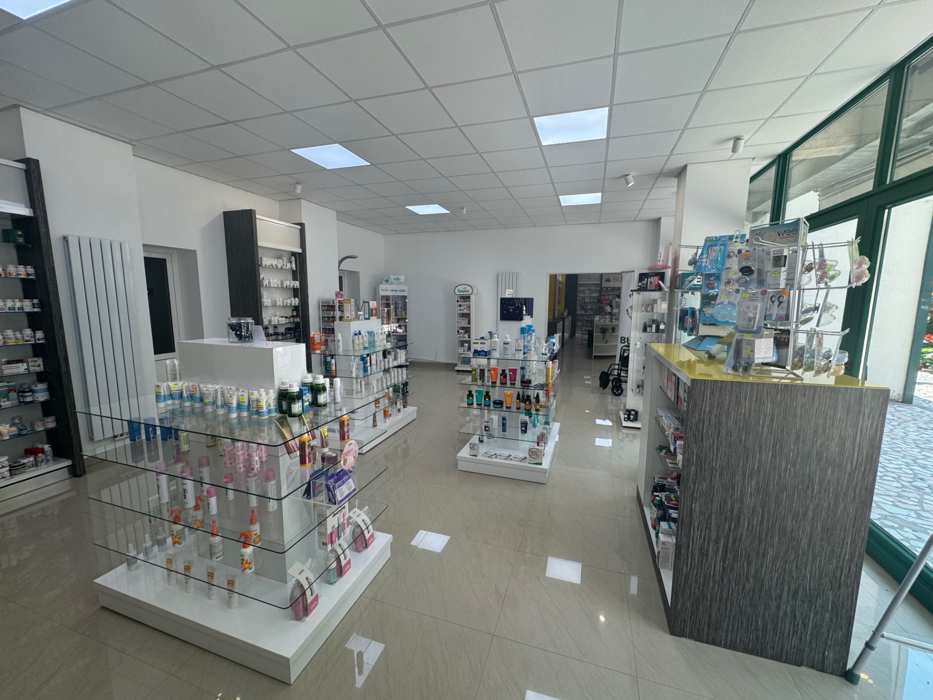 Spațiul central al farmaciei BUJOR FARM cu rafturi cosmetice și produse